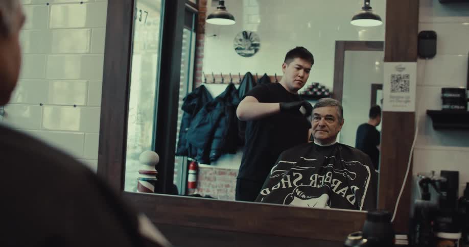 A man cutting another mans hair at a barber shop