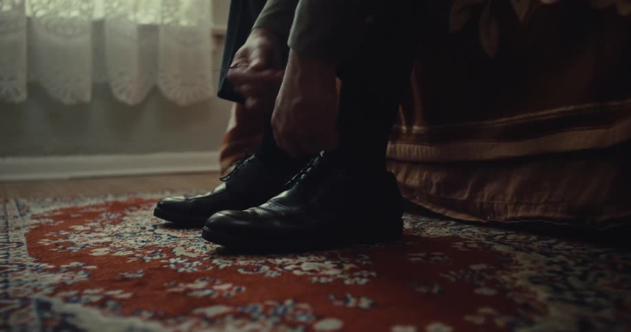 A young man wearing black shoes and black socks indoors at midday