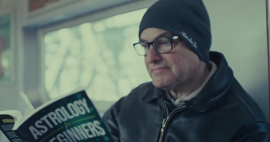 Man reads a book as he sits on a train