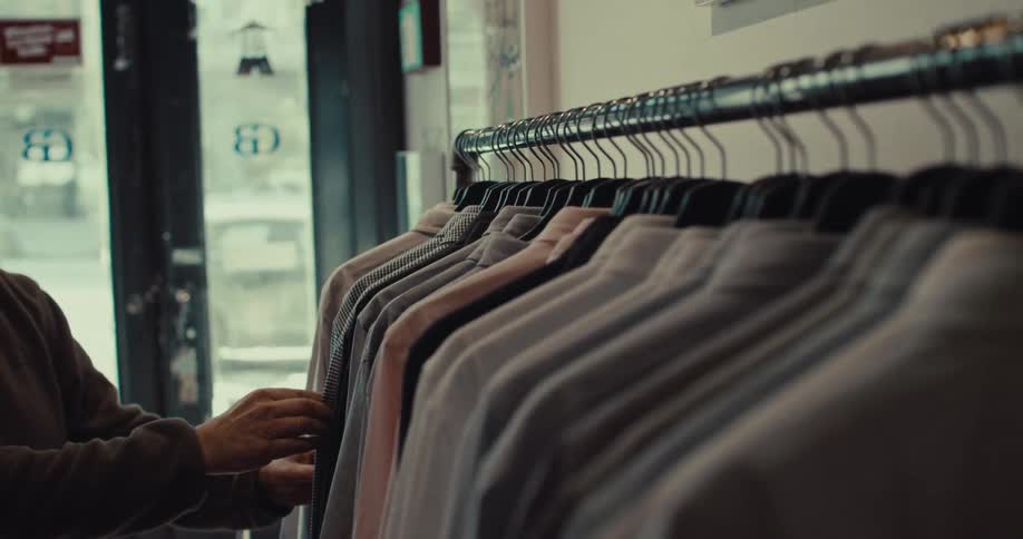 Man looks through shirts on a rack in a clothing store