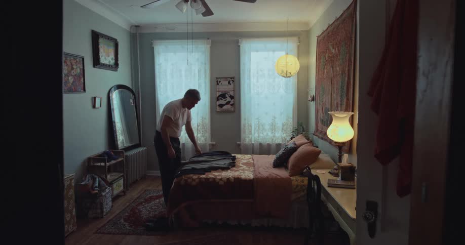 A man choosing clothes while standing in a brightly lit bedroom