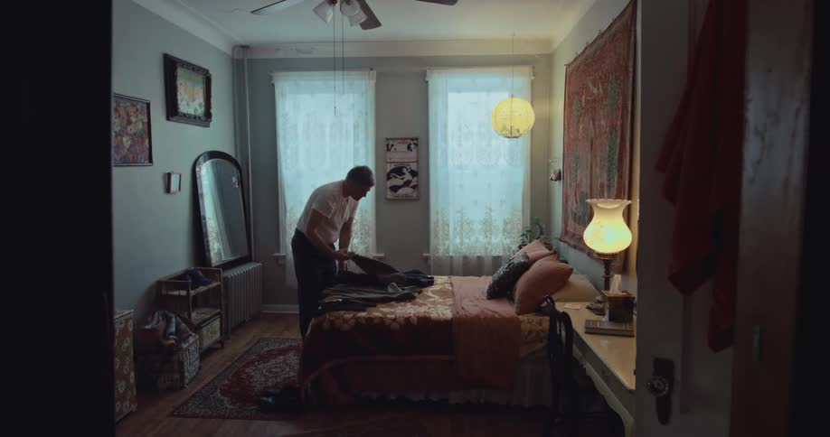 A man stands in his bedroom while picking out an outfit to wear