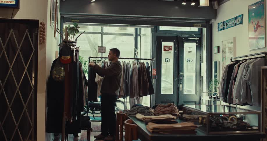 Man stands in a clothing store looking at shirts on the rack