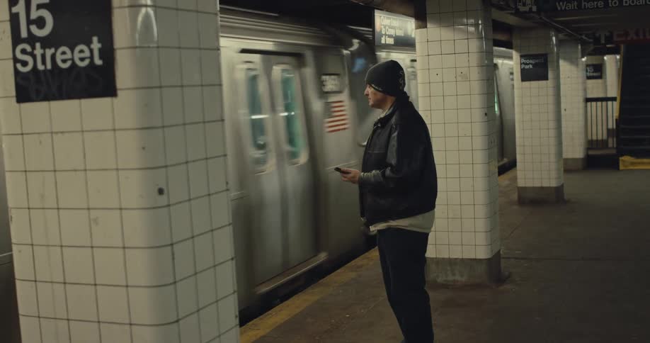 Man waits on platform while subway train passes through 15 street station