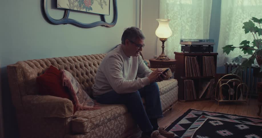 The man is texting on his phone at home