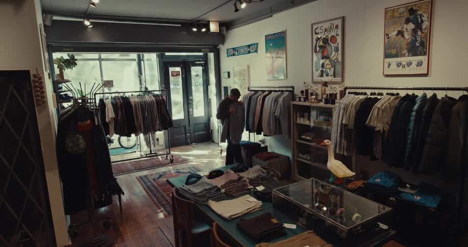 A man checking out clothes on a hanger inside a clothing shop at midday