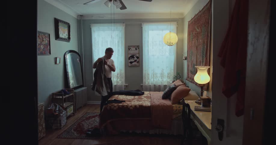Man stands in his bedroom looking at a shirt and jacket lying on the bed