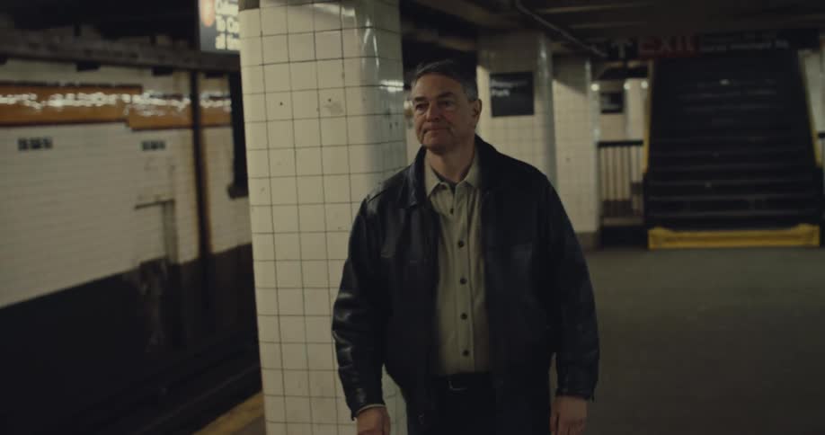 Man takes his phone out of his pocket as he walks in the subway station