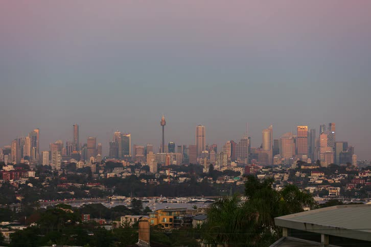 Dawn light illuminates urban skyline under pinktoned sky