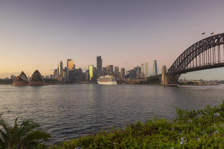 A time lapse captures the transition from night to dawn over sydney harbor featuring the illuminated city skyline harbor bridge and opera house