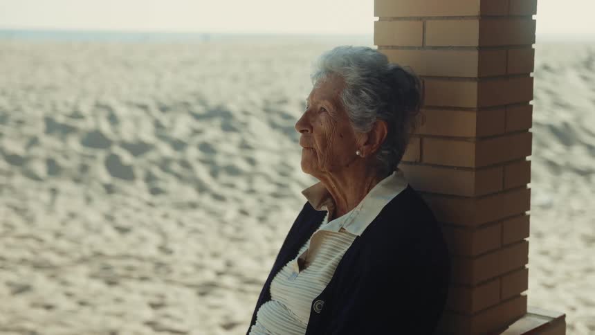 The woman is sitting outside by the sand