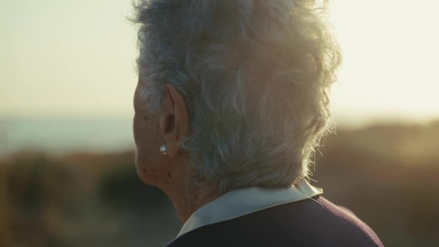 Profile of an elderly person with gray hair illuminated by sunlight