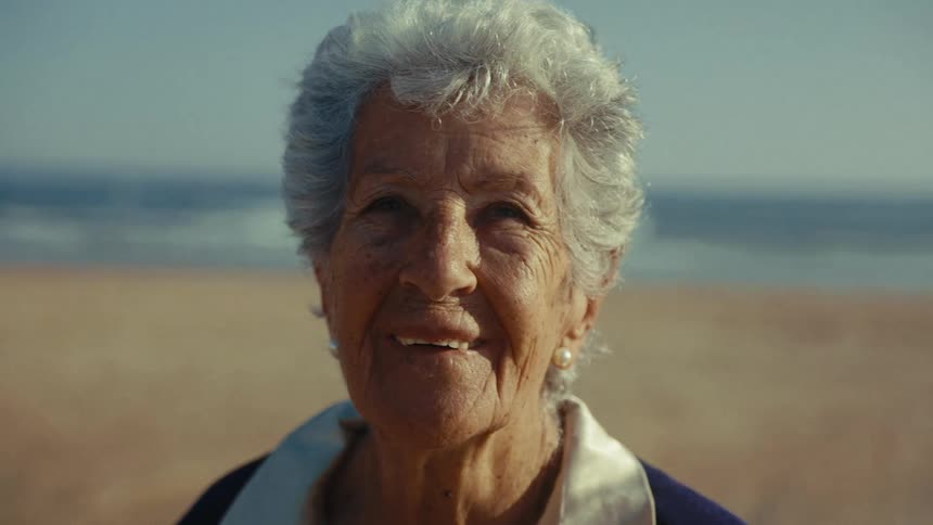 The woman smiles on the beach and puts on her sunglasses