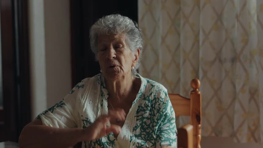 Elderly woman sitting at a table talking indoors