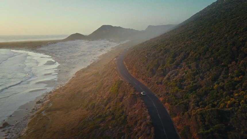 An aerial view of a car driving near the coast