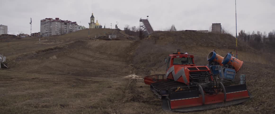 Maintenance machine parked on hillside with jump ramp and church in the background