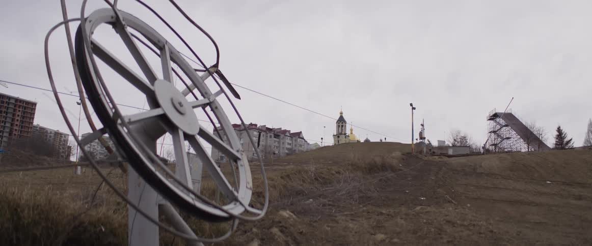 The most prominent is the long diagonal cable line stretching from the large metal pulley in the foreground up toward the top of the hill this line serves as the functional path for the lift system cutting through the open space