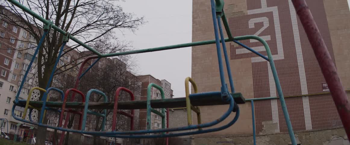A swing moving slowly left and right due to wind in a playground in the citty at midday