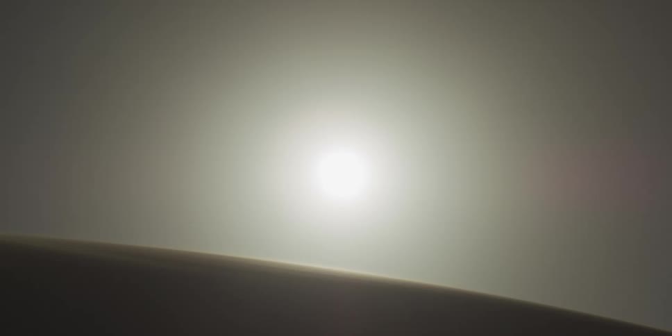 Sun shines above the crest of a desert dune