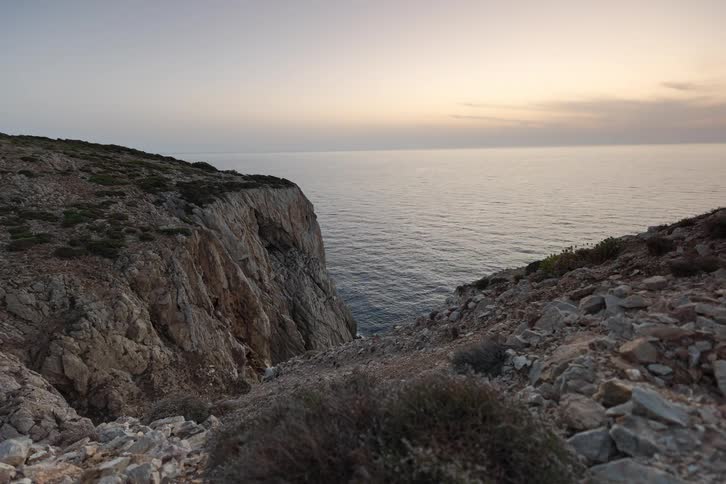 Sunset over calm sea viewed between coastal rocky cliffs
