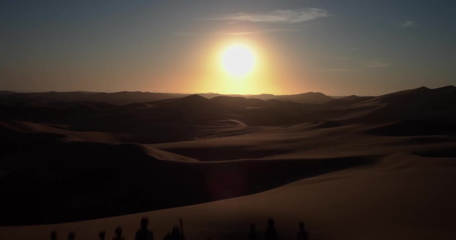Silhouettes of people on a dune at sunset