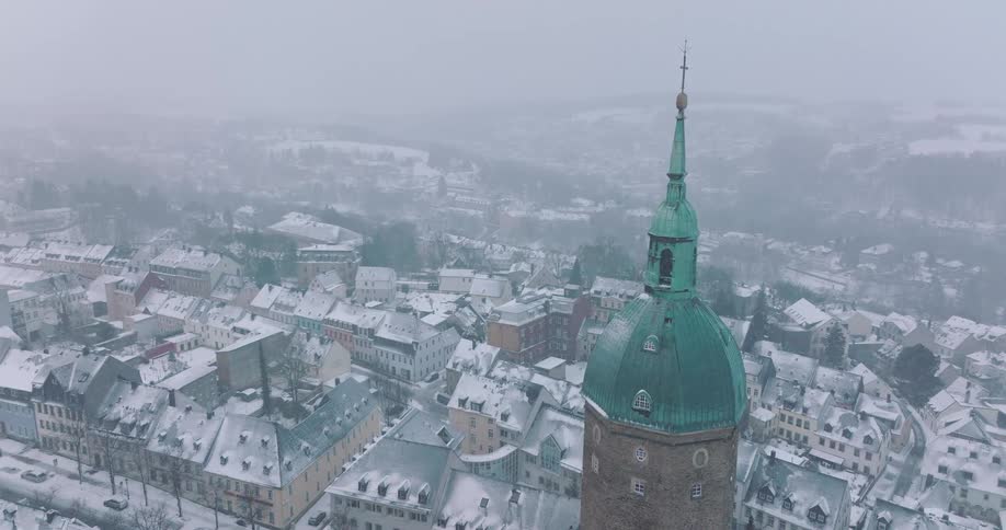 Church tower with green dome above snowcovered town