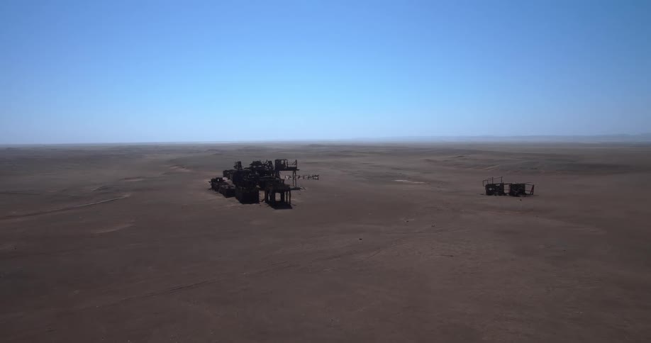 Abandoned metal structures in desert plain under clear sky