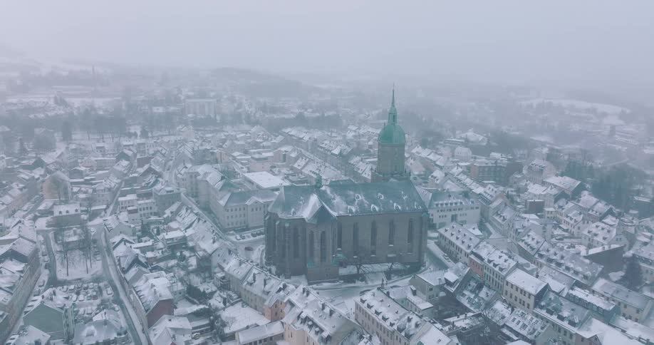 A cityscape at midday with residential building rooftops covered in snow during winter