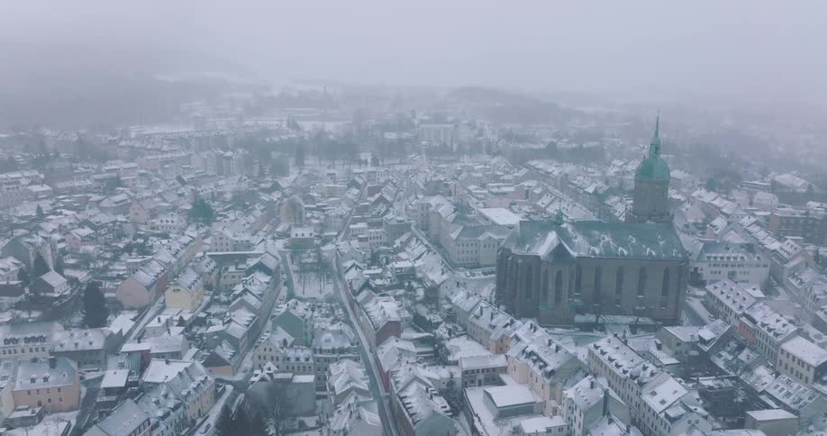 Haze partially obscures buildings in snowy neighborhoods located near a cathedral on a winter day