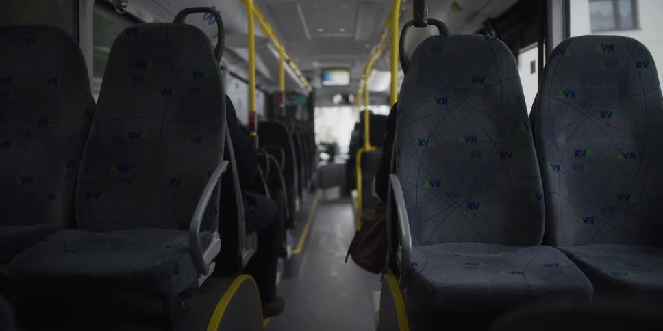 An empty bus driving in the middle of the city at midday