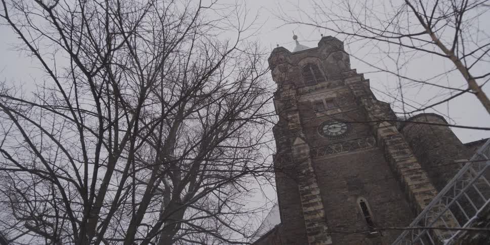 The exterior of a tower on a church on a snowy day