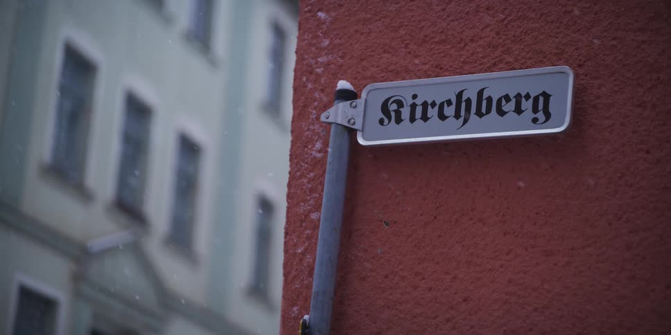 Street sign with the name kirchberg mounted on an orange wall