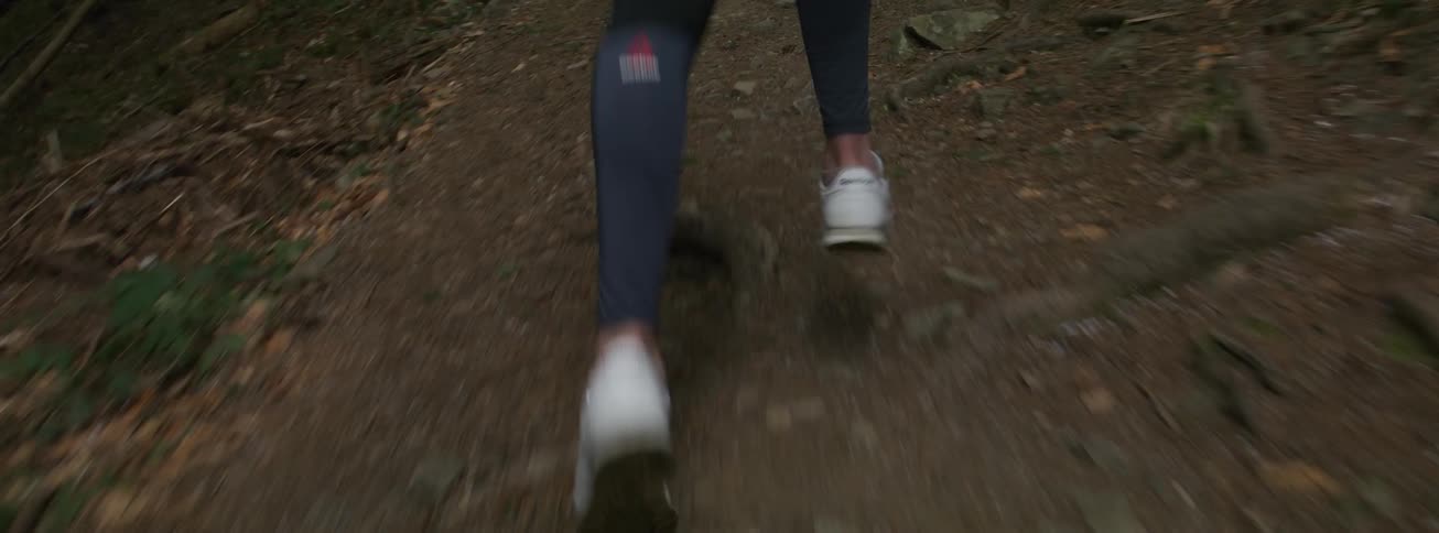 Person running along dirt trail in a forest