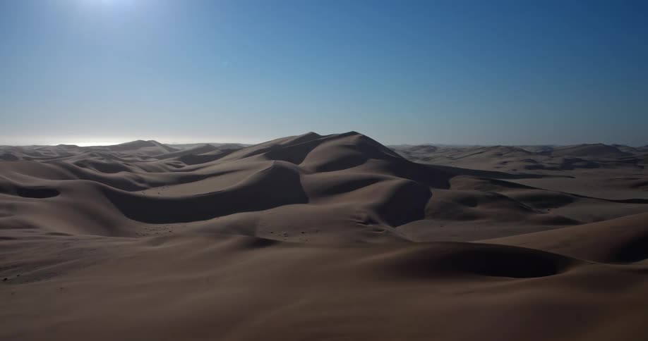 Aerial footage of a wide open desert landscape under a sunny sky