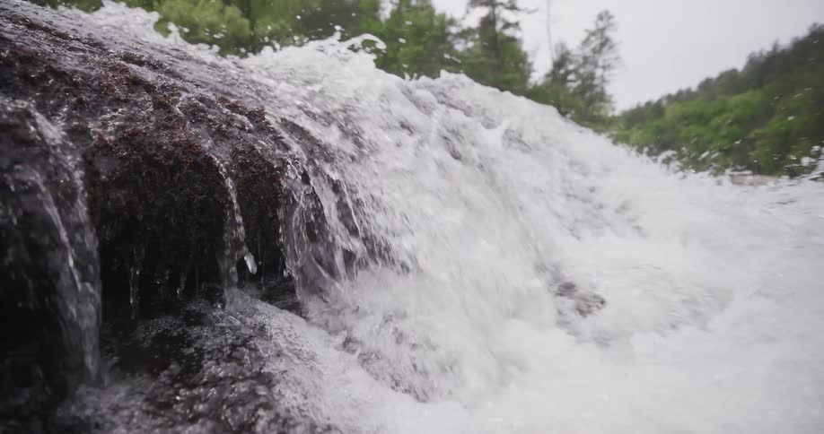 Water splashes as a waterfall flows over the edge of rocks in the river