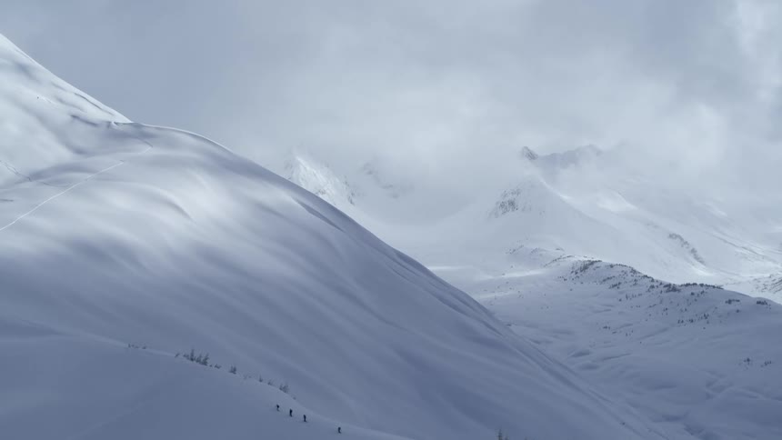 A group of people skiing up a snowy mountain in the arctic at midday