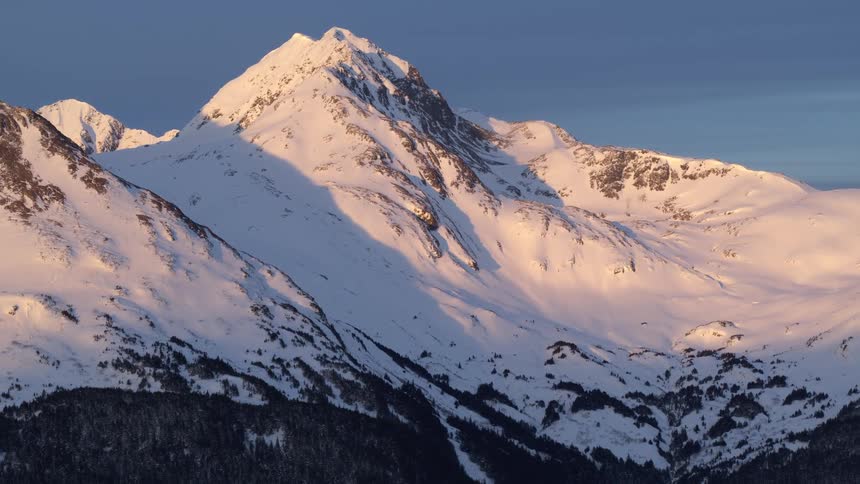 Sunlight shines on snow covered mountains
