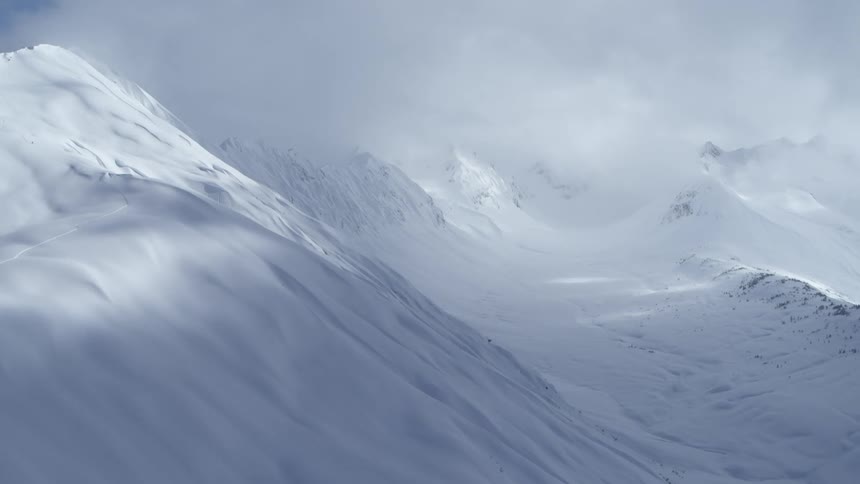 Heavy snow cover on mountains across the landscape under a cloudy winter sky