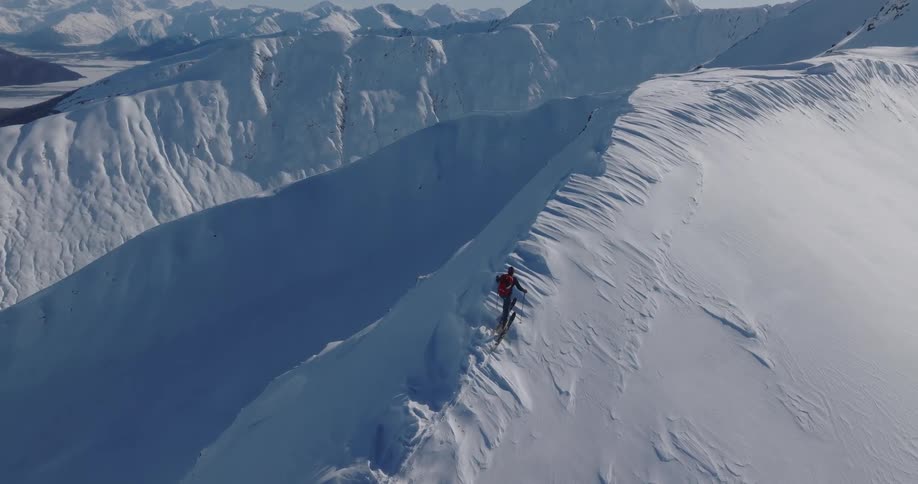 Skier holds his poles as he makes his way up a snow covered mountain slope