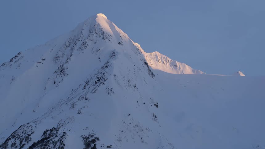 Sunlight shines on a snow covered mountain ridge