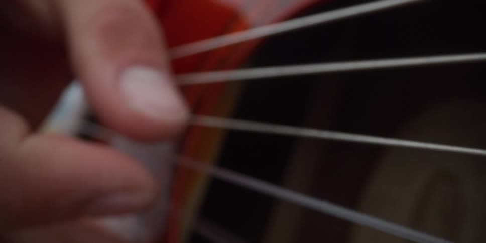 Musician strums the strings of an acoustic guitar