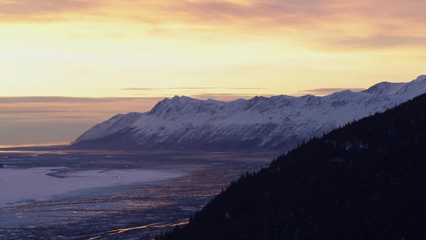 Forested mountain on the coast with snow covered mountains on the peninsula