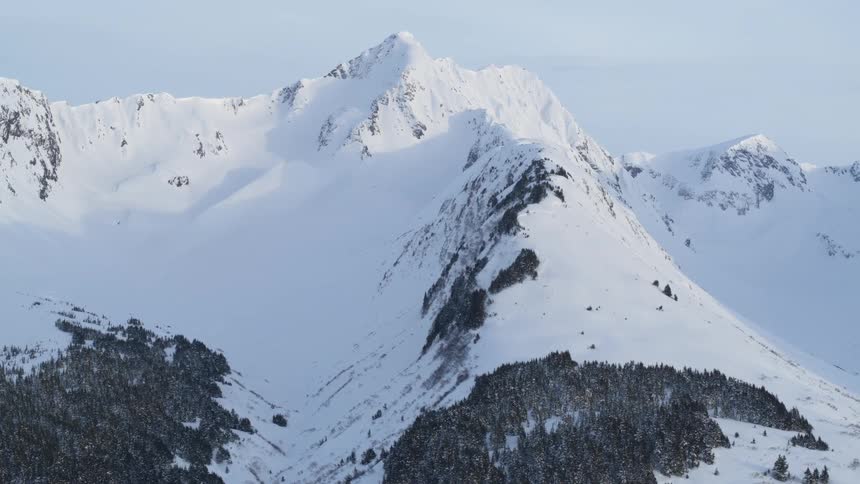 A mountain range in the arctic covered in snow at midday