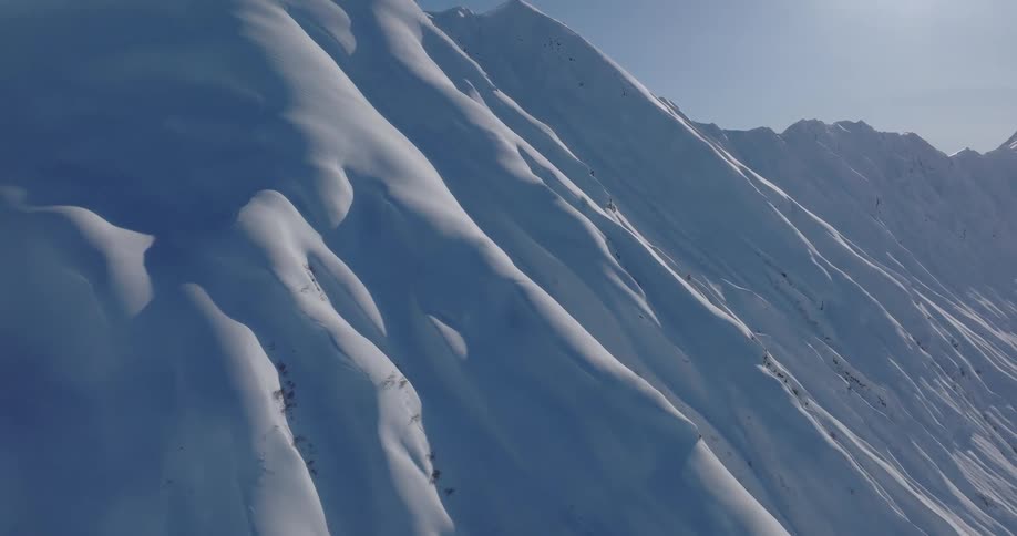 Snow covers steep mountain slopes on a sunny winter day