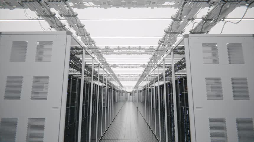 A view through a bright corridor of a modern data center shows long rows of white server racks with glowing lights and organized cables under a clean white ceiling