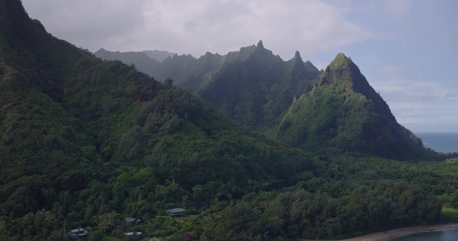 A majestic aerial view showcases the stunning green peaks and lush valleys of a tropical coastline meeting the sea