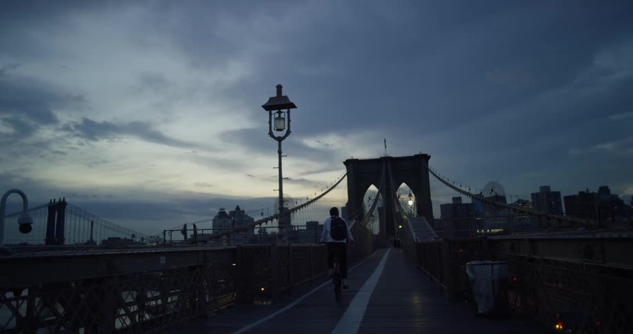 A man rides across a bridge at dawn