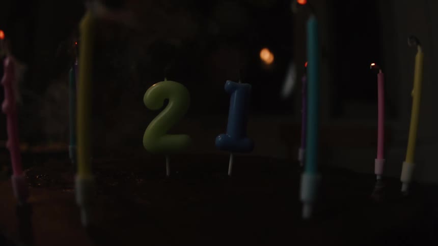 Close up of a 21st birthday cake with candles being blown out in slow motion