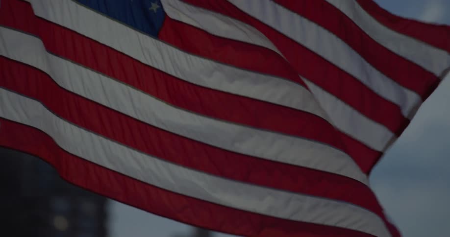 American flag waving with buildings in the background