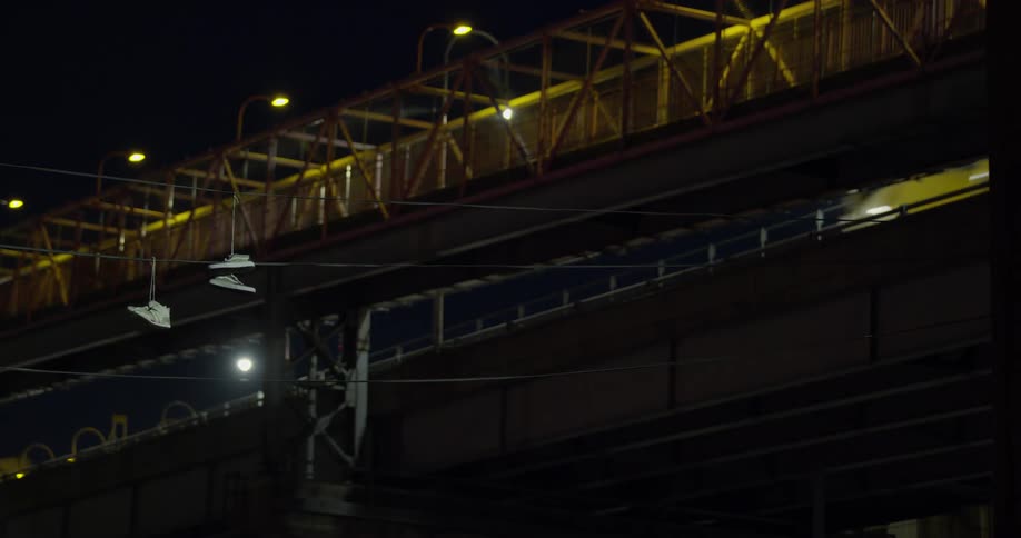 Vehicles pass over the bridge above at night
